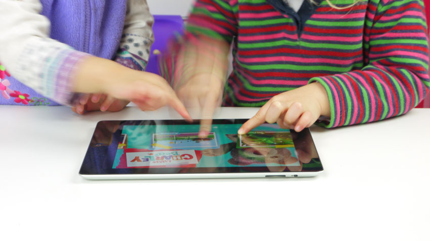 2 toddlers touching tablet screen